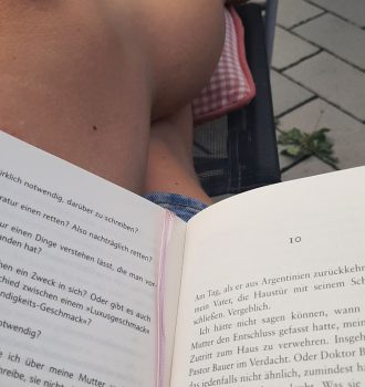 aufgeschlagenes Buch auf Beinen, die auf einem Stuhl liegen