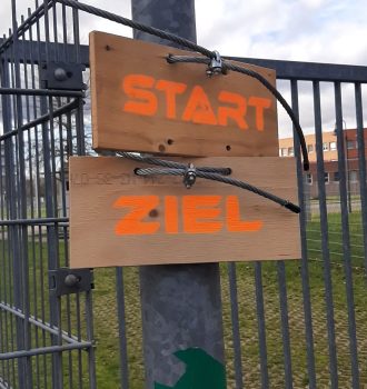 Start- und Zielschild an einem Zaun